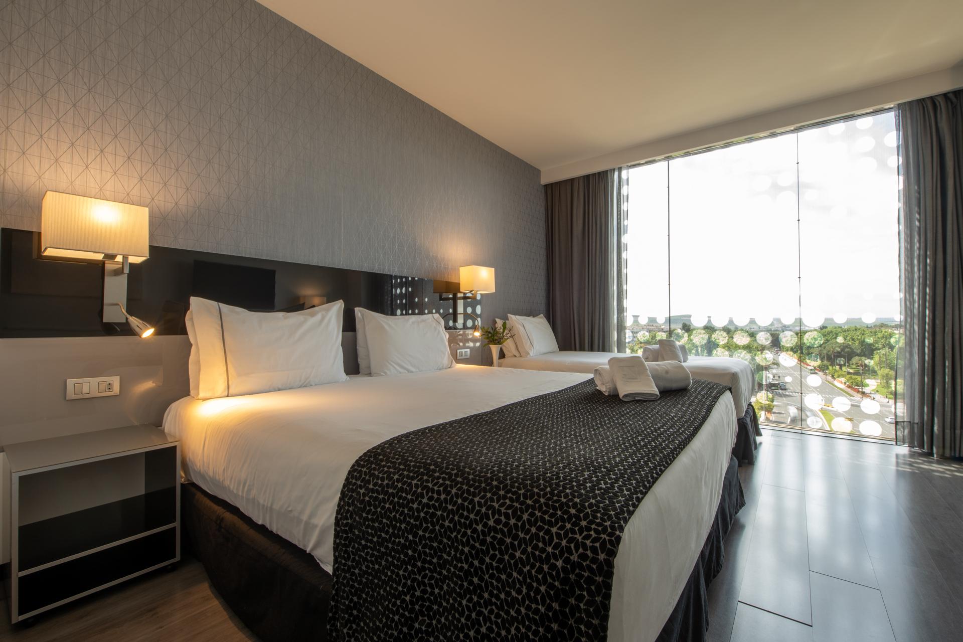 ยูโรสตาร์ส พาเลซ โฮเต็ล Hotel กอร์โดบา ภายนอก รูปภาพ The photo shows a modern hotel room featuring two large beds with white linens and dark patterned bedspreads. Each bed has a set of pillows and a decorative cushion. There are bedside lamps on either side of the beds, and a contemporary piece of furn