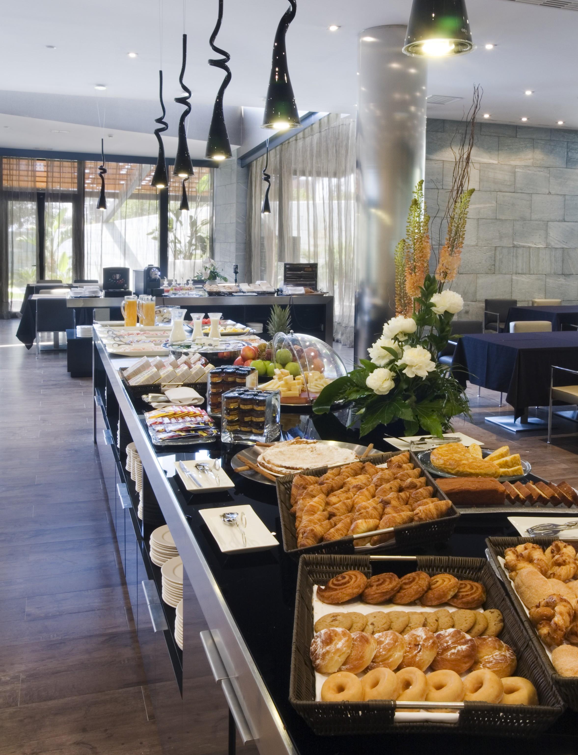 ยูโรสตาร์ส พาเลซ โฮเต็ล Hotel กอร์โดบา ภายนอก รูปภาพ The photo shows a beautifully arranged buffet spread in a modern setting. There are various dishes displayed on a long table, including pastries, desserts, fruits, and baked goods. A decorative arrangement of flowers enhances the presentation. The ba