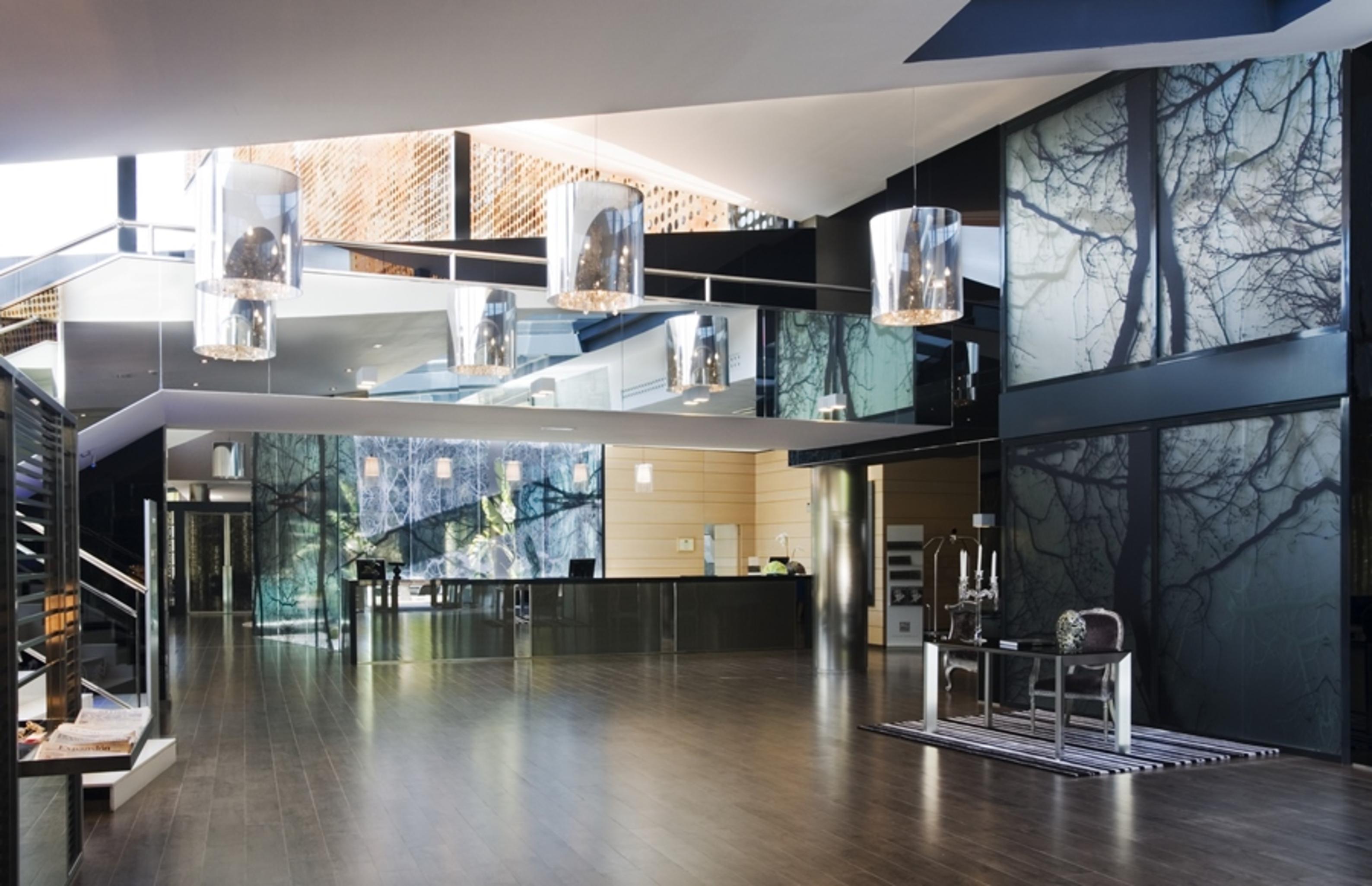 ยูโรสตาร์ส พาเลซ โฮเต็ล Hotel กอร์โดบา ภายใน รูปภาพ The photo shows a modern interior space, likely an entrance or lobby area. The design features:

- A spacious layout with a polished wooden floor.
- Large glass panels that reflect light, creating an open and airy feel.
- Artistic wall décor that inc