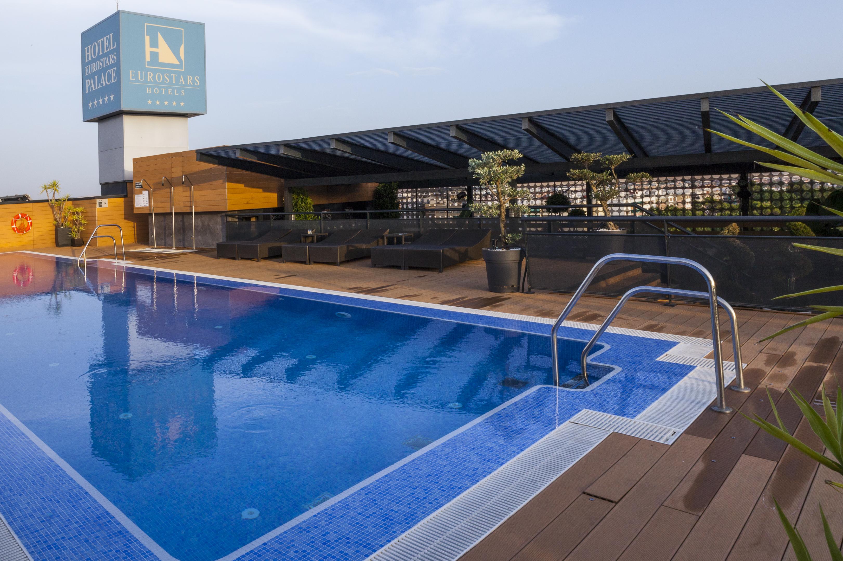 ยูโรสตาร์ส พาเลซ โฮเต็ล Hotel กอร์โดบา ภายนอก รูปภาพ The photo shows a rooftop swimming pool with a clear blue water surface. There is a section of the pool with a ladder for entry, and the surrounding area includes wooden decking. In the background, there is a sign for a hotel, which appears to be nam