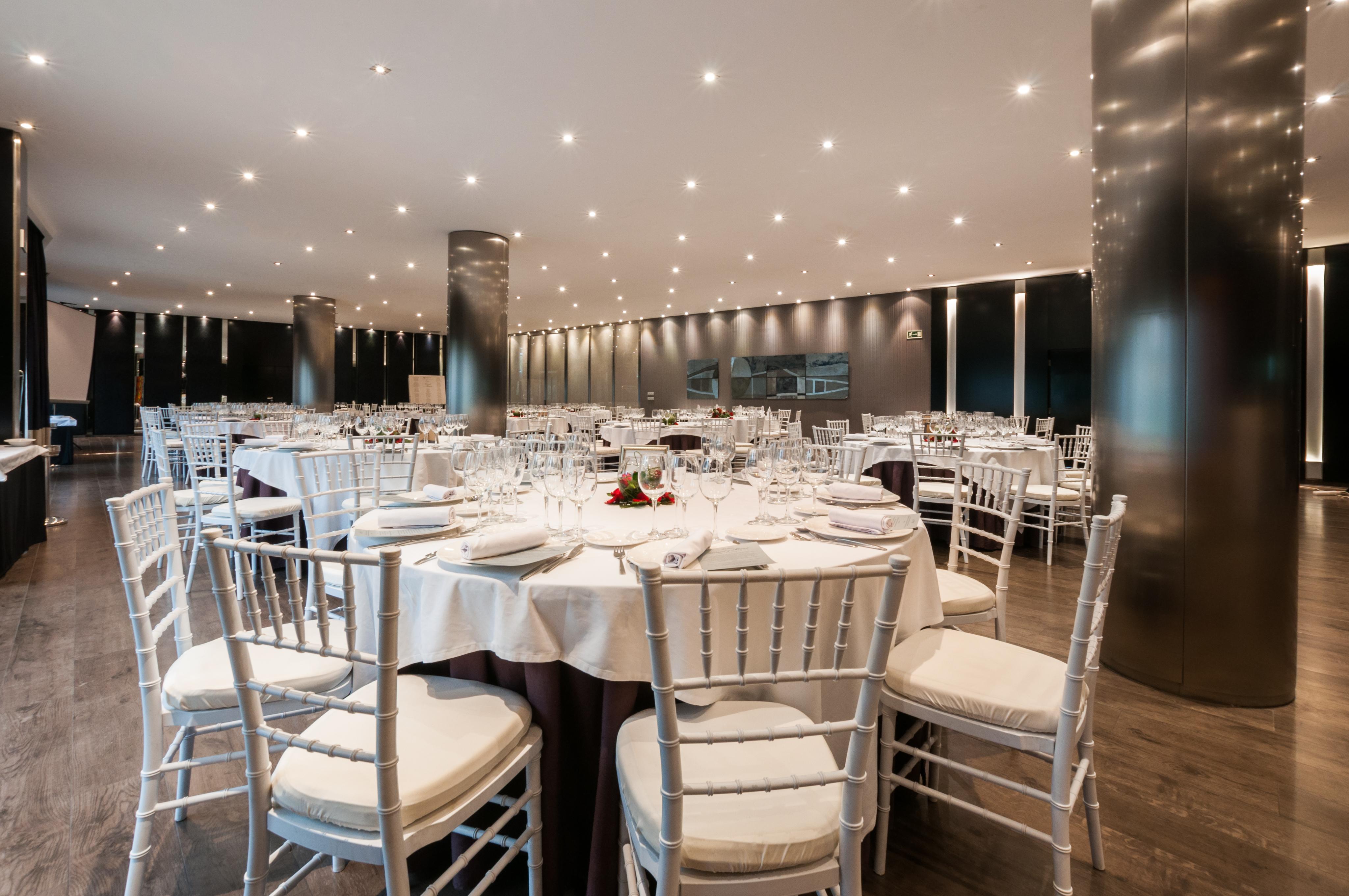 ยูโรสตาร์ส พาเลซ โฮเต็ล Hotel กอร์โดบา ภายนอก รูปภาพ The photo shows an elegant dining setting in a spacious restaurant. There are several round tables, each with white tablecloths and neatly arranged place settings, including glasses, plates, and utensils. The chairs are white with padded seats, provi