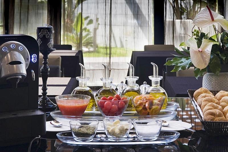 ยูโรสตาร์ส พาเลซ โฮเต็ล Hotel กอร์โดบา ภายนอก รูปภาพ The photo displays a stylish breakfast or brunch spread on a table. In the foreground, several small glass containers hold various ingredients: there are glasses filled with different types of oil, a bowl of fresh red tomatoes, a bowl of mixed fruit,