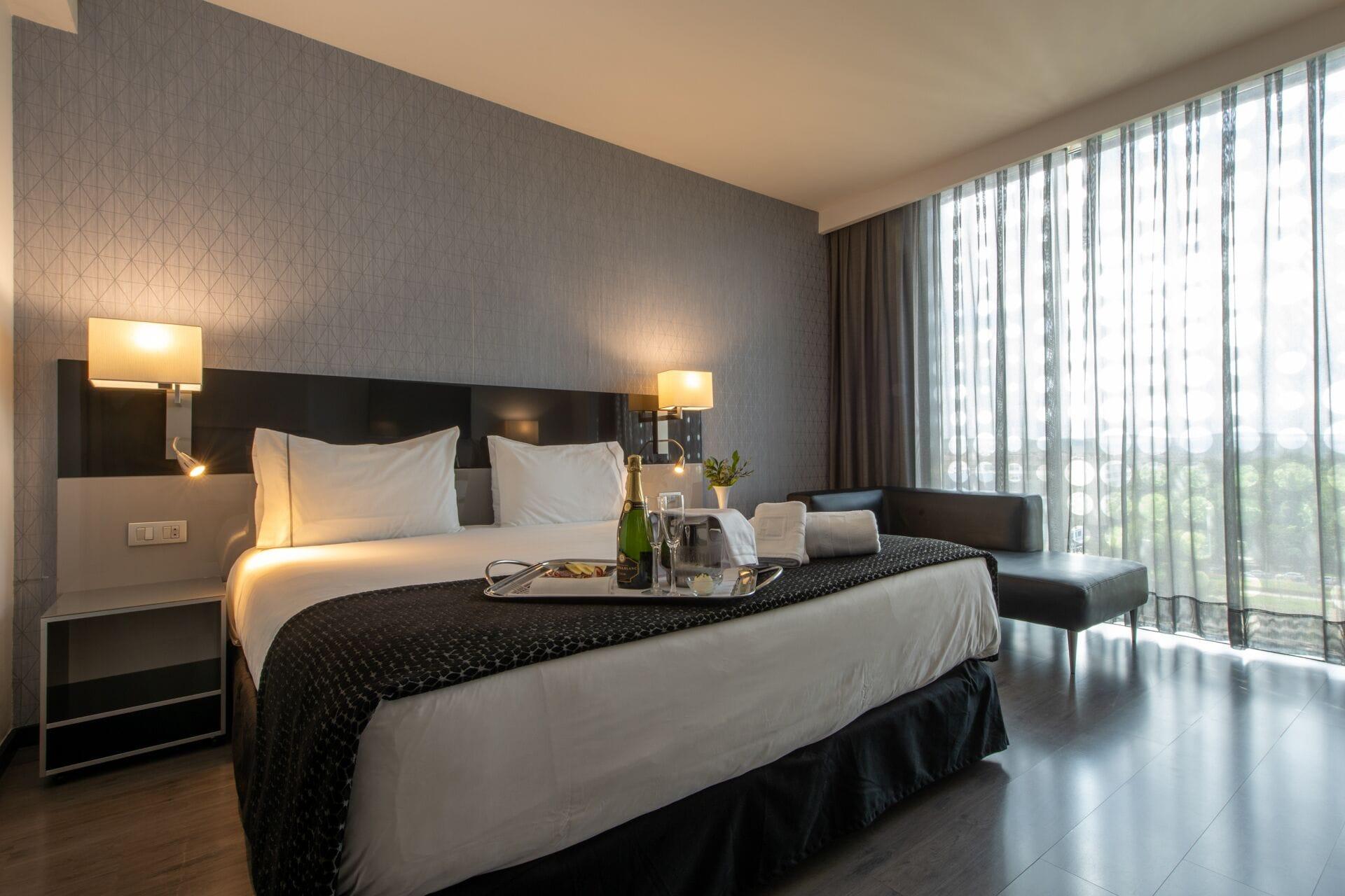 ยูโรสตาร์ส พาเลซ โฮเต็ล Hotel กอร์โดบา ภายนอก รูปภาพ The photo shows a modern hotel room featuring a large bed with crisp white linens and dark throw blankets. On either side of the bed, there are bedside lamps providing soft lighting. The room has a sleek design with a neutral color palette, including