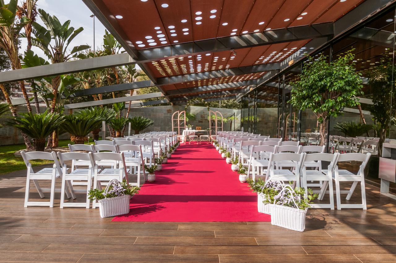 ยูโรสตาร์ส พาเลซ โฮเต็ล Hotel กอร์โดบา ภายนอก รูปภาพ The image shows an outdoor wedding setup. There are white chairs arranged neatly on either side of a vibrant red carpet that leads to a framed archway. The area is covered by a glass and metal structure, allowing plenty of natural light, while tropic