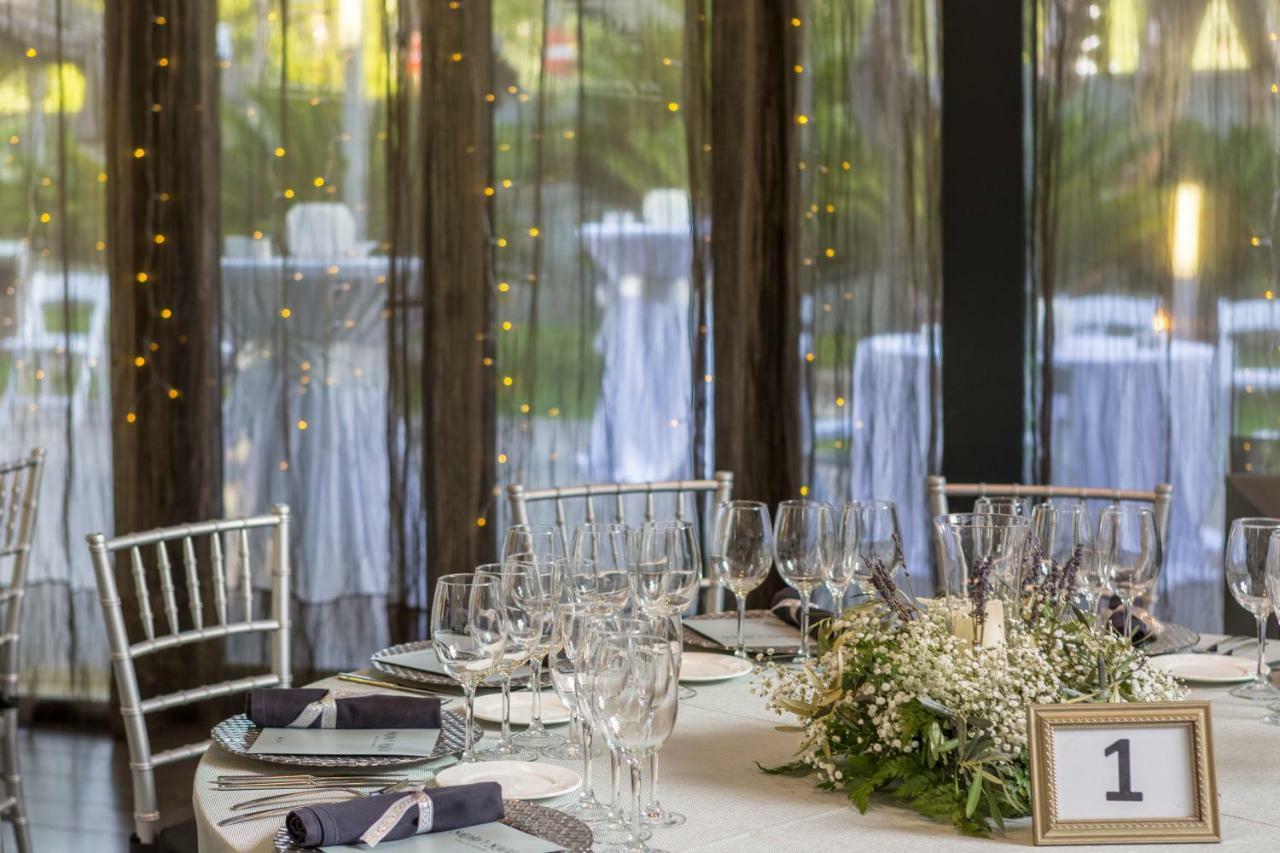 ยูโรสตาร์ส พาเลซ โฮเต็ล Hotel กอร์โดบา ภายนอก รูปภาพ The photo shows a beautifully set dining table in an elegant event space. The table is round, covered with a white tablecloth, and adorned with a centerpiece of greenery and flowers. There are several wine glasses and water glasses arranged neatly on